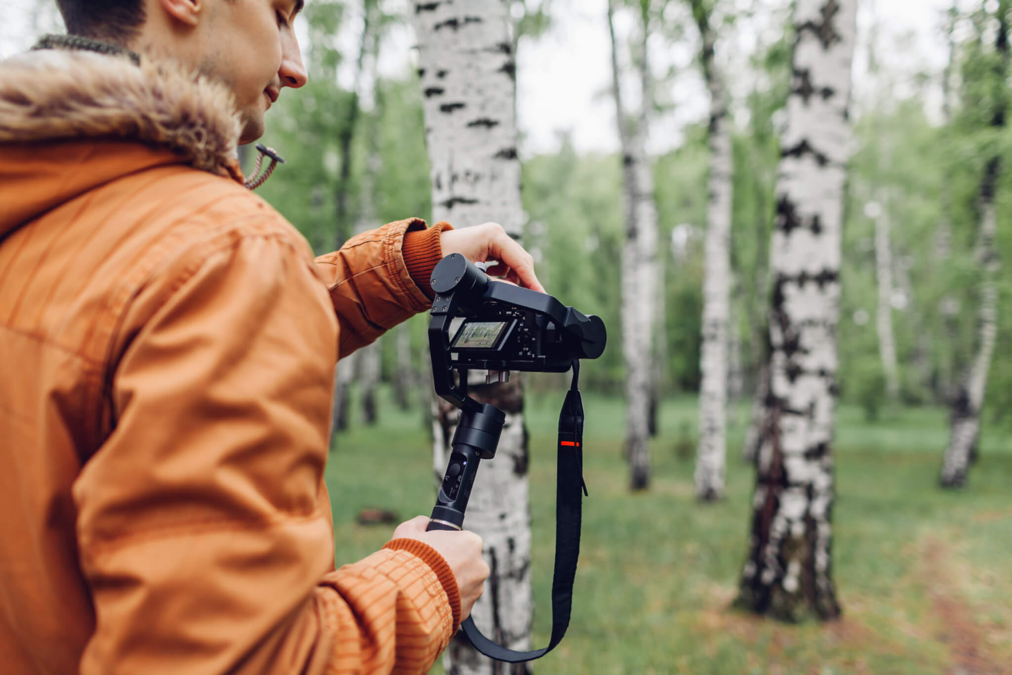 Jeune homme tient un monopode avec appareil photo dans la forêt