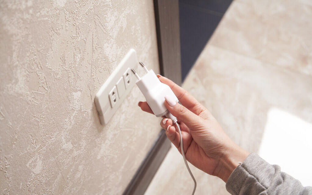 Une femme débranche le chargeur de son téléphone